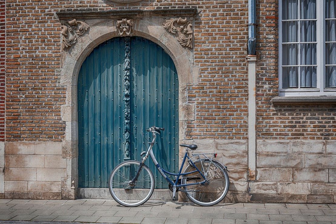 Tegelfasad med en blå damcykel parkerad framför en blå port